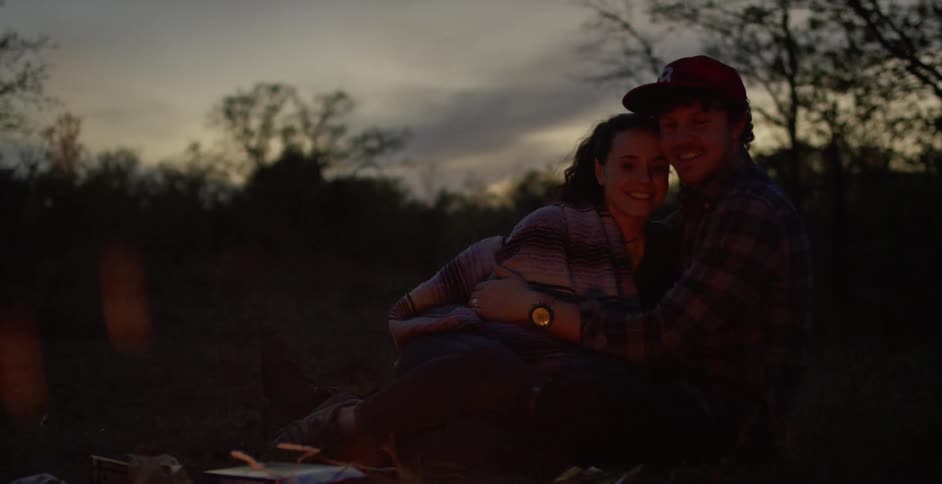 Boyfriend and girlfriend are sitting by a bonfire together