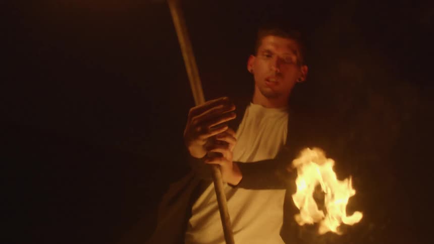 Man spins sticks of fire around his body outside at night