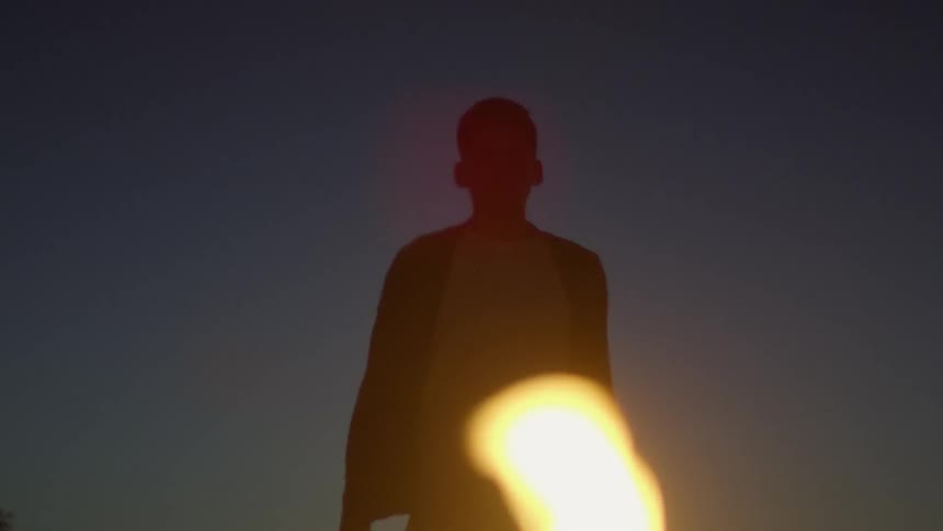 A man walks in the dark by a campfire