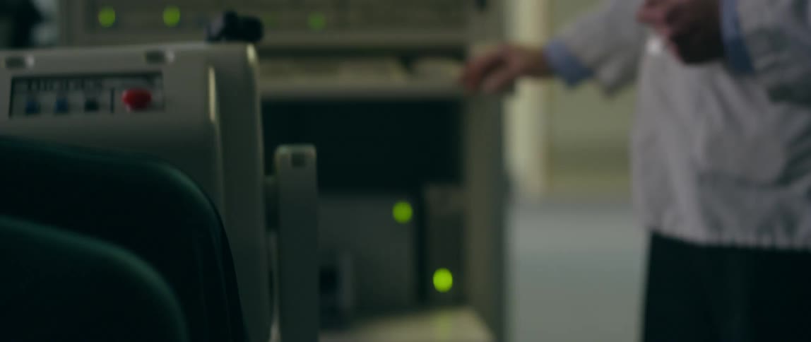 Person sits in a chair kicking their leg back and forth as a doctor looks at a monitor