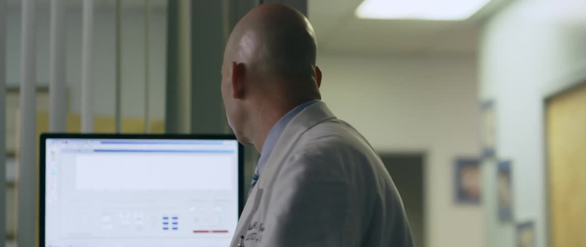 A doctor talks as he looks at a monitor