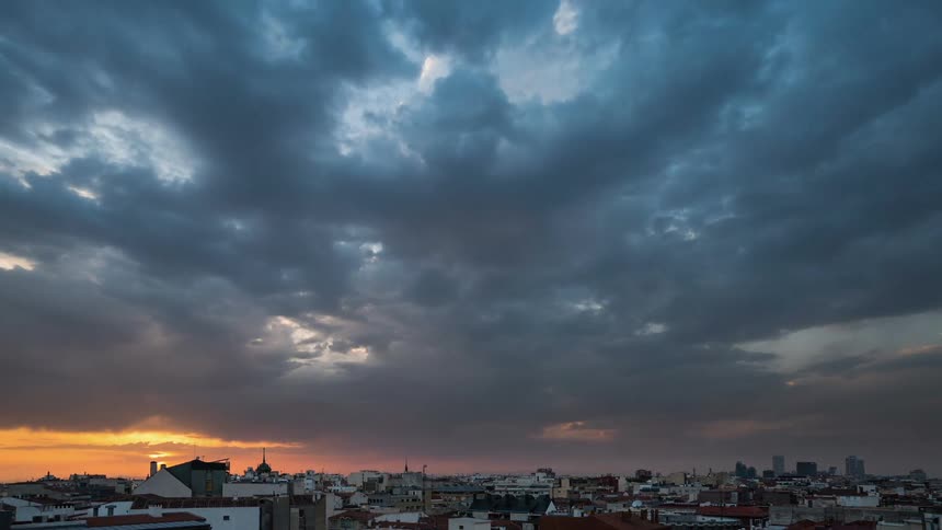 Clouds move over a town at sunset