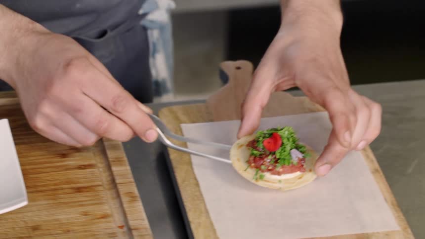 A chef picks up an appetizer and moves it off of a plate