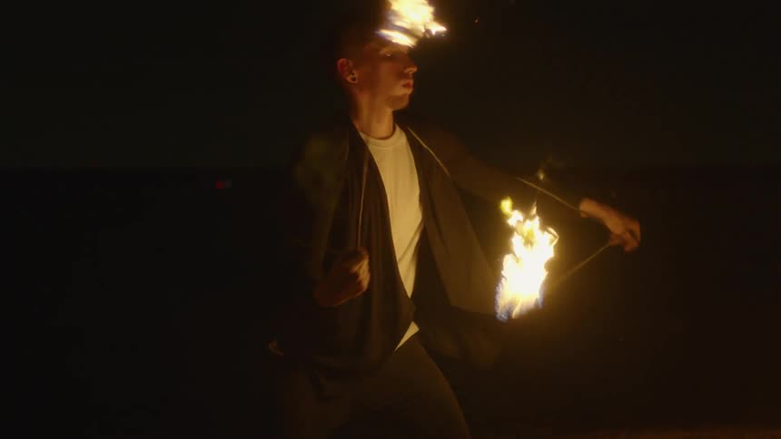 The man is twirling fire at night