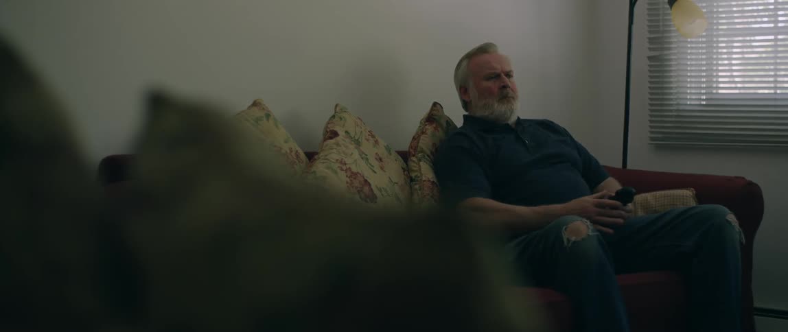 Man sits on a couch with many pillows on it