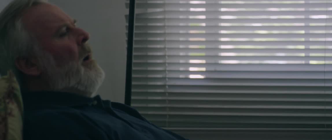 Short of breath man sits down in a chair and leans back