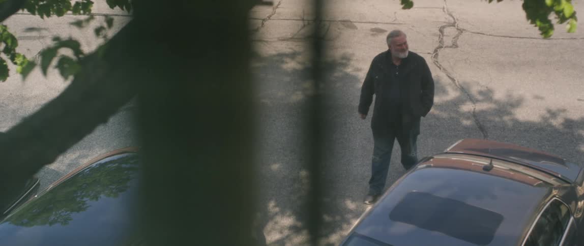 Man walks in a parking lot in between two cars