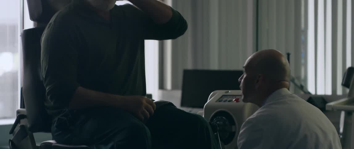 A physical therapist adjusts equipment for a man in a chair
