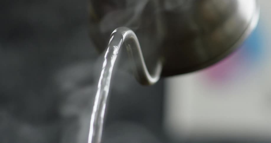 A pitcher pouring boiling water with steam rising