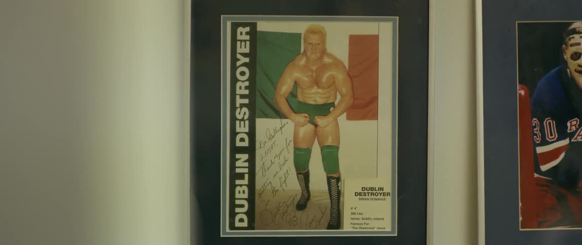 A framed and autographed poster of a wrestler hanging on a wall