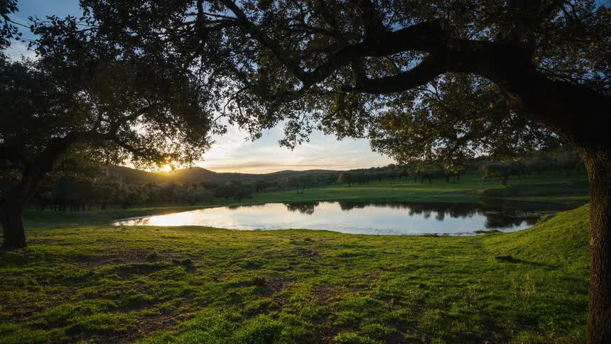 Sun sets behind hills and is reflected in a lake