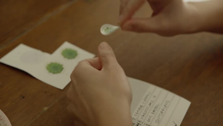 A woman puts a sticker on her postcard