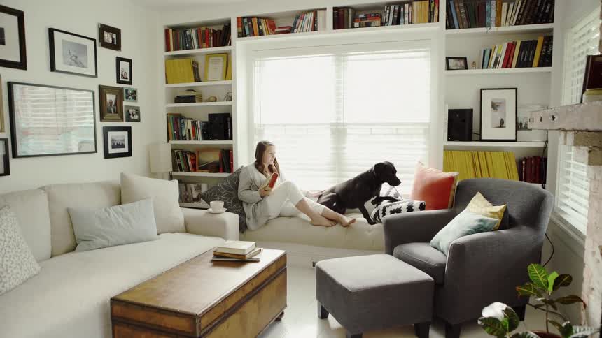 A woman is sitting on the windowsill with her dog