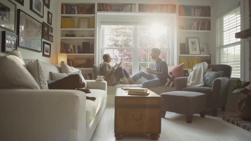 A couple sit on a window seat reading and drinking coffee