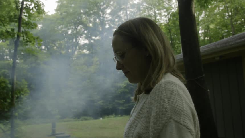 A woman sways back and forth as smoke blows past