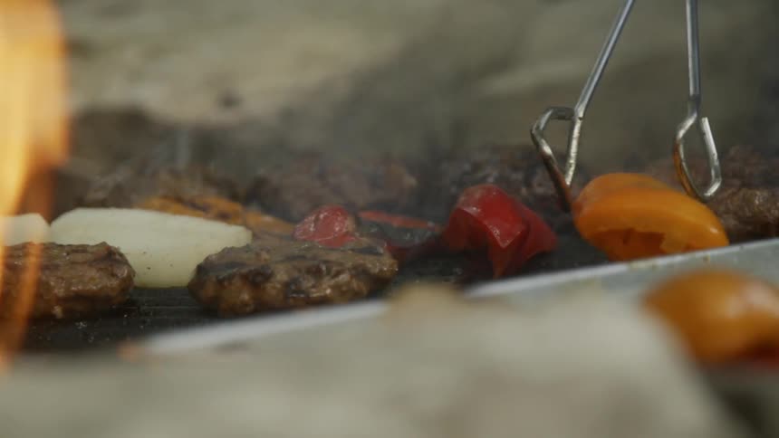 Person flips food over on a grill with tongs