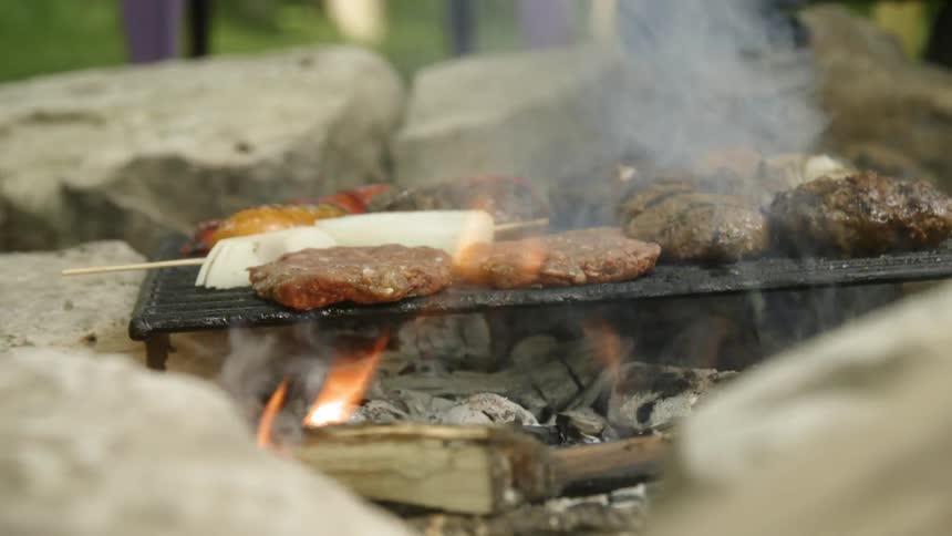 Person puts food on a grill rack over a fire put