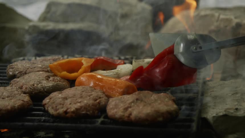 Peppers are flipped over on a flaming grill