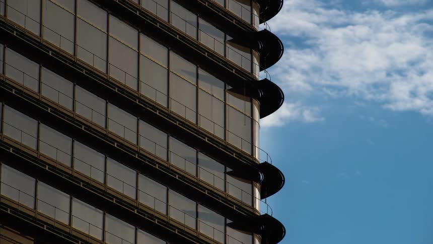 Clouds move in the blue sky over a tall building