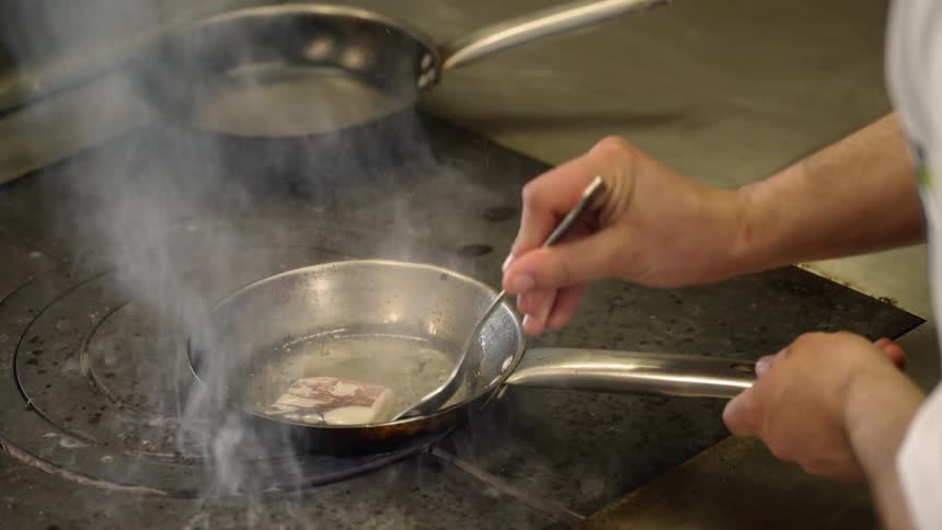 A chef is cooking food in the small pan