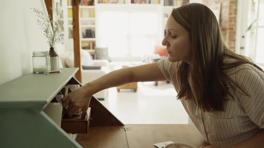 Woman counts piece of paper in a small desk drawer