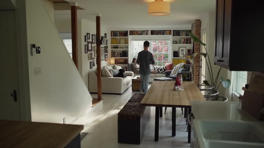 Man walks into the living room and hands a mug to a woman