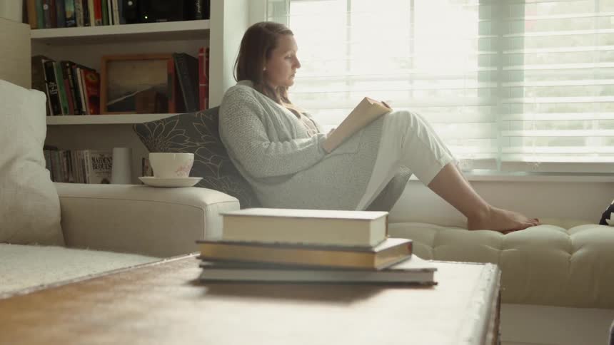Woman Leans Back and Reads in a Window Seat