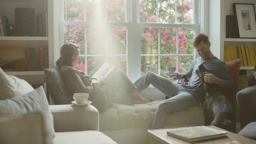 Man pets a dog while sitting on the couch with a woman