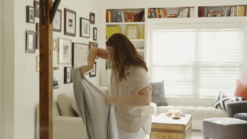 Woman Puts Sweater on at Home