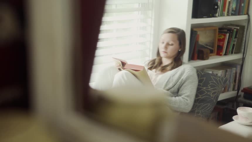 The woman is reading a book by the window
