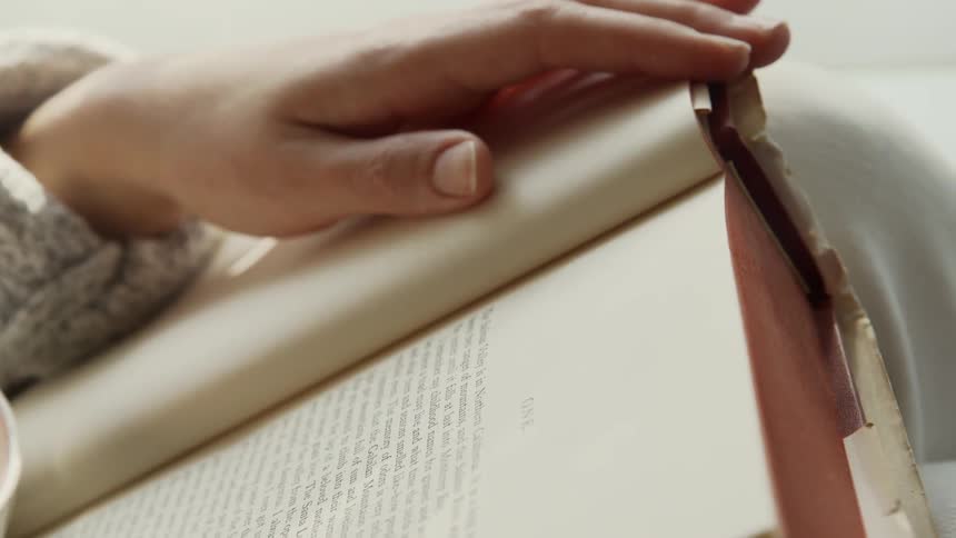 Person reads a book while resting their hand on one page