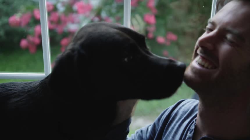Man smiles as a dog licks his face