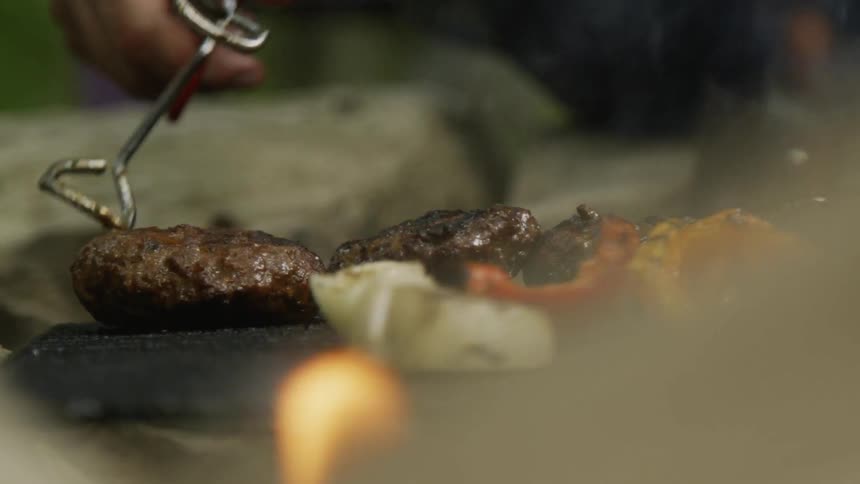 Person flips food over on a grill with tongs