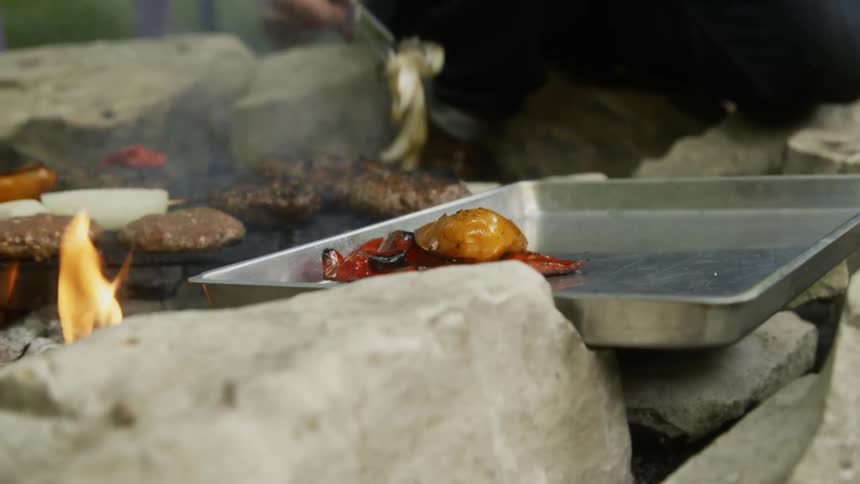 Man uses tongs to remove the cooked food from the hot grill