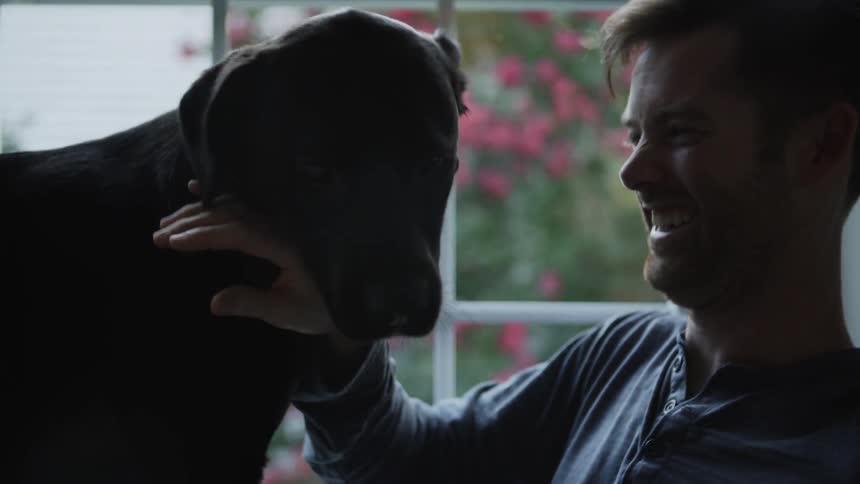 Man laughs as a dog licks his face