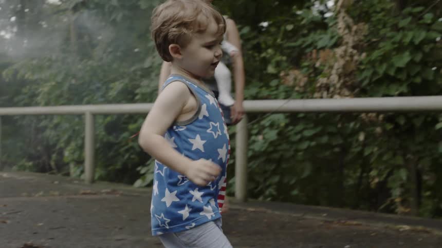 A mom looks on as her son runs through some smoke on the path