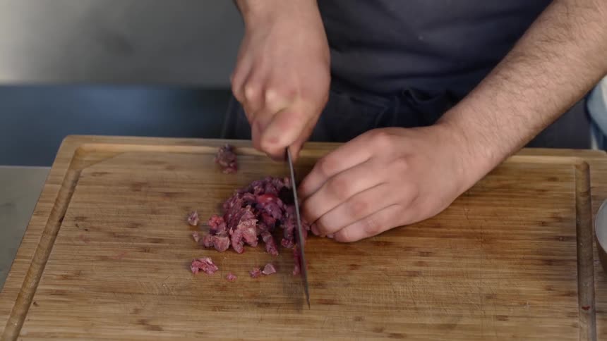 A man chops meat on a cutting board