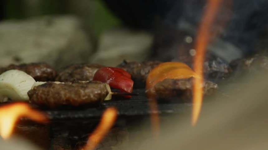 Meat and vegetables cook on the grill over a hot fire
