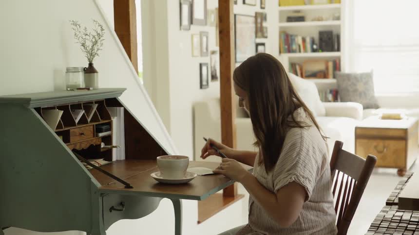 Woman takes the cap off of a pen then prepares to write on a piece of paper
