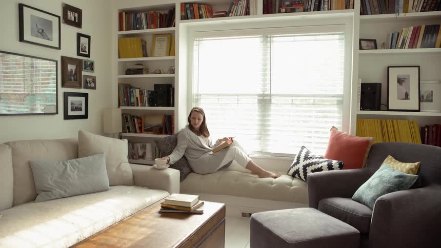 Woman sits on a sofa and reaches for a coffee cup