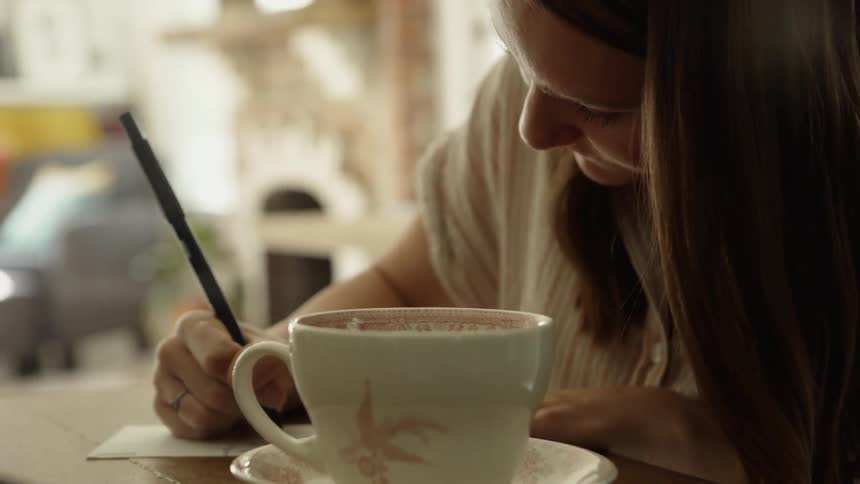 Woman writes on the back of a postcard