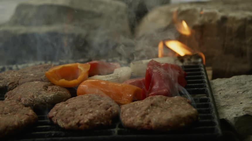 Person puts food on a smoking grill