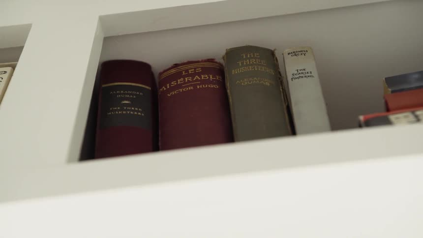 Books lined up in a row on a white shelf