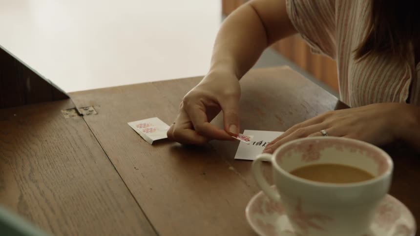 A woman places a stamp on a postcard