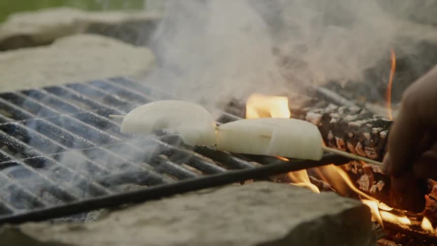Person puts a skewer of vegetables on the grill
