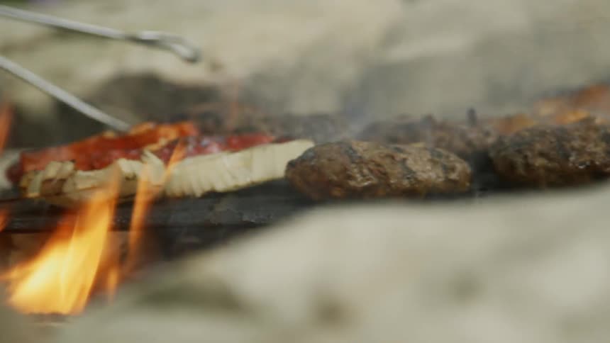 Person flips food over on a grill over a smoking fire