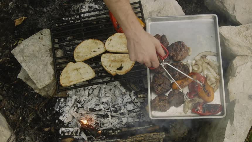 A man arranges food on a tray after taking them off the grill