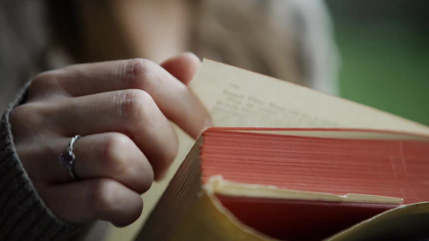 A woman turns the page of a book