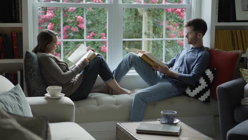 A couple sits on a window seat reading