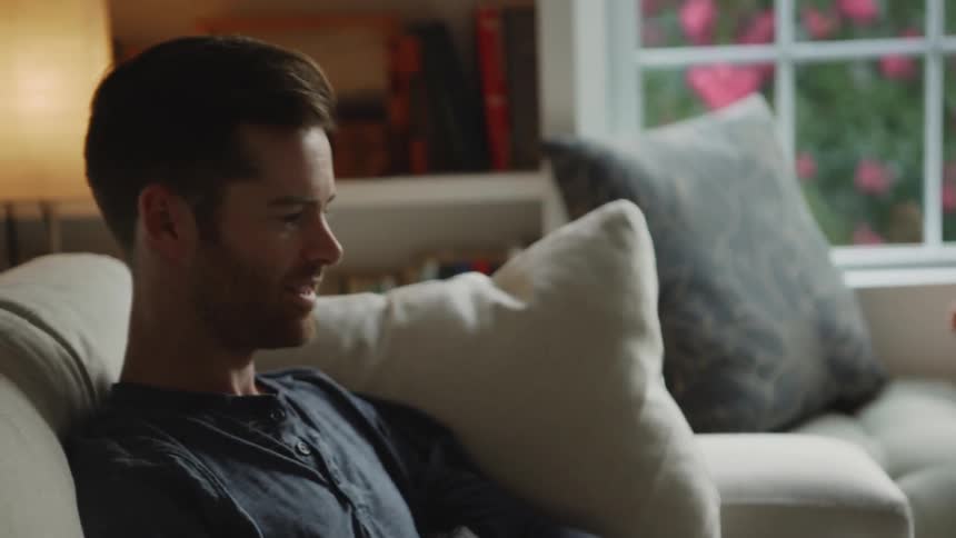 Man sits on the couch and looks over smiling